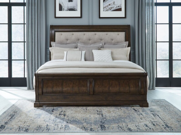 Elegant bed with pillows and framed photos on wall.