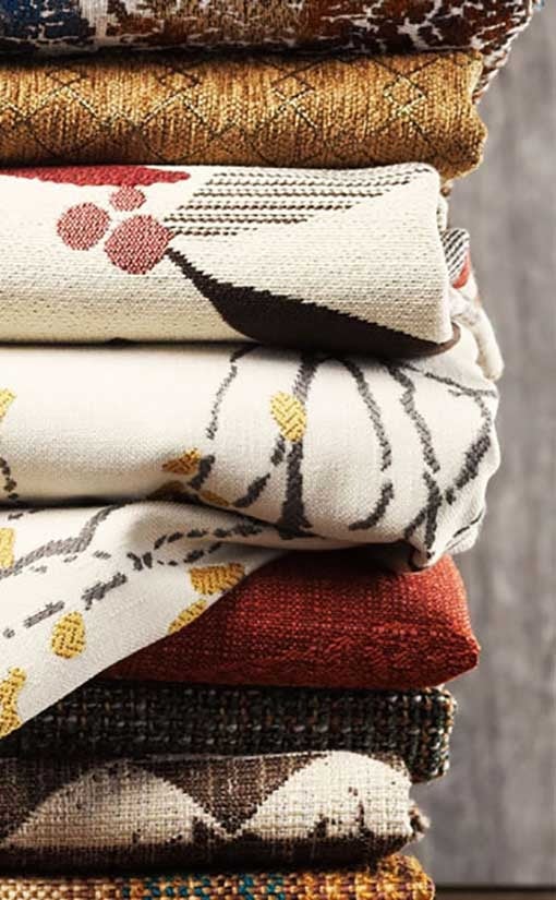 Stack of colorful patterned fabric rolls.