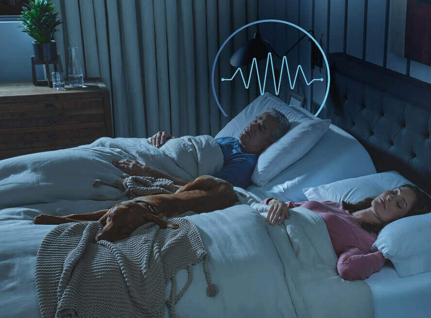 Couple sleeping with dog in bed, sound wave overlay.